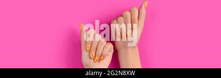 Des mains de femmes soignées avec un motif à ongles tendance sur fond rose Banque D'Images
