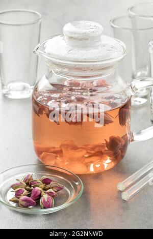 Théière en verre avec thé des boutons de rose séché comme boisson chaude aromatique Banque D'Images