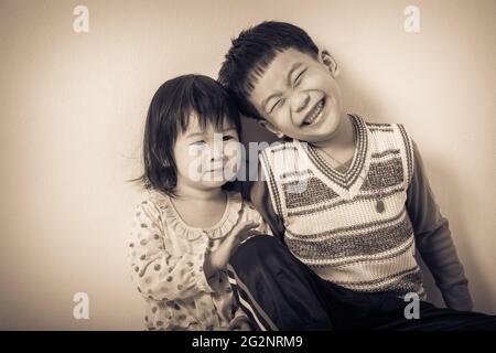 Petits enfants asiatiques (thaïlandais) heureux, frère et sœur souriant, aimant et liant de concept frère et sœur. Fond crème. Style d'image vintage Banque D'Images