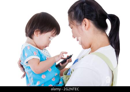 Jeune mère portant sa fille, adorable petite fille asiatique (thaï) tenant et jouant le gadget électronique (développement de l'enfant et apprentissage), isolé Banque D'Images