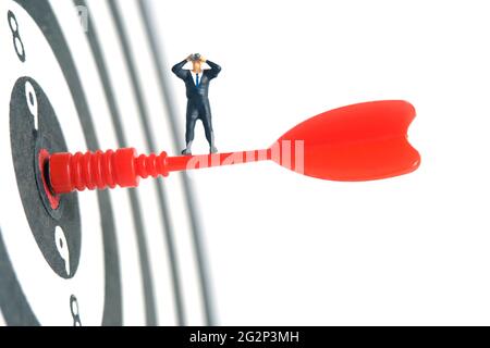 Hommes d'affaires debout au-dessus de la flèche rouge sur le plan de travail à l'aide de jumelles. Photo miniature de jouets de personnes minuscules. Isolé sur fond blanc. Banque D'Images