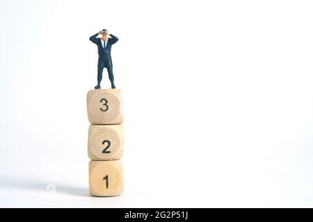 Photographie miniature de jouets de personnes. Un homme d'affaires regardant, recherchant, observant à l'aide de jumelles au-dessus des dés isolés sur fond blanc. Banque D'Images
