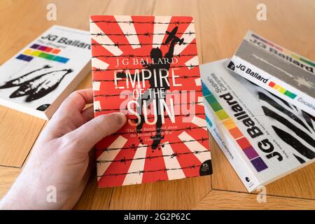 Main d'un homme tenant un livre de poche de l'Empire du Soleil, un roman de l'époque de la guerre de l'âge de l'auteur anglais J. G. Ballard Banque D'Images