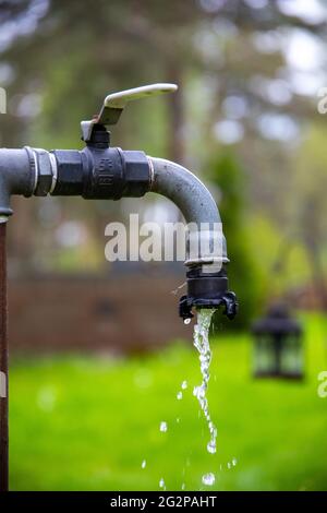 Plan vertical d'un robinet d'eau avec de l'eau courante à l'extérieur par une journée ensoleillée Banque D'Images