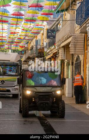 Jérusalem, Israël - 3 juin 2021 : parasols colorés suspendus sur une rue de Jérusalem, Israël, et reflétés dans les pare-brise de voitures. Banque D'Images