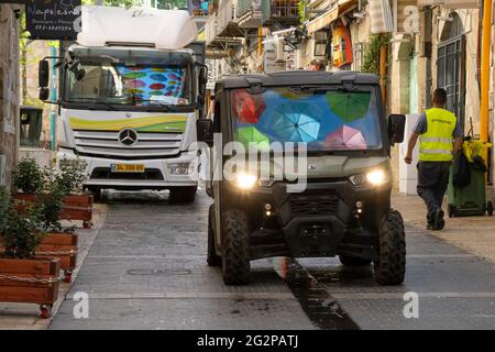 Jérusalem, Israël - 3 juin 2021 : parasols colorés suspendus sur une rue de Jérusalem, Israël, reflétés dans les pare-brise de voitures. Banque D'Images