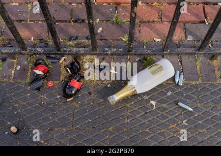 Bouteille de bière cassée, bouteille de champaign et bouteille d'oxyde nitreux en métal riant les canons à gaz sur le trottoir à côté d'une clôture en métal. Londres - 12 juin 2021 Banque D'Images