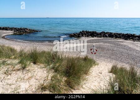 Une belle plage vide derrière des dunes de sable avec des grins de tempête rocailleux pour se protéger de l'érosion et d'une station de secours Banque D'Images