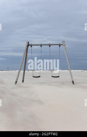 Deux balançoires sur une plage de sable doré vide avec la mer des Wadden du nord de l'Allemagne en arrière-plan Banque D'Images