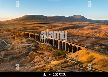 Lumière du matin dorée sur les arches de Viaduc de Ribblehead entourées de larges landes ouvertes. Pris avec un drone dans le parc national de Yorkshire Dales, Royaume-Uni. Banque D'Images