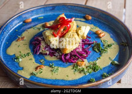 Poulet Satay présenté sur une assiette bleue et photographié en gros plan sous lumière naturelle. Banque D'Images