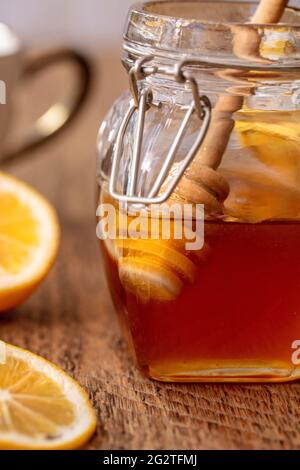 Pot de miel égoutté d'un bâton de miel avec un côté de citron sur une table en bois Banque D'Images