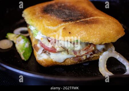 Jambon de prosciutto maison, fromage, tomate, et sandwich ciabatta d'oignon grillé sur une poêle en fonte avec pain ciabatta grillé Banque D'Images