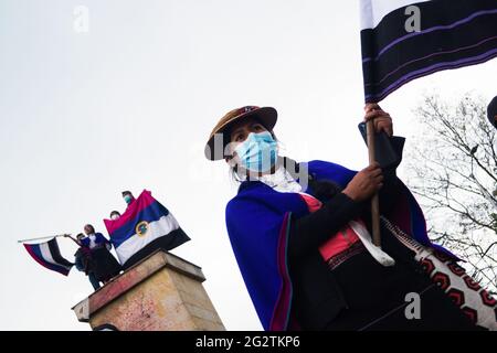 Une femme du peuple autochtone Misak prend la place de 'Monumento a los Reyes Catolicos'. Dans cette place spécifique se trouvaient les sculptres de Chrisropher Columbus et Isabel la Catolica, quelques jours avant qu'ils ne tentent de retirer ces sculptures et de riposter par la police nationale colombienne. Les sculptres ont été ramenés par le ministère de la culture la nuit qui a suivi les affrontements. À Bogota, Colombie, le 11 juin 2021. Banque D'Images