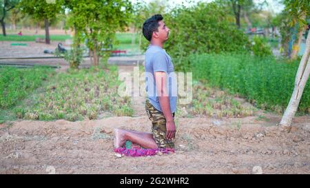 Homme en bonne santé faisant de l'exercice d'étirement sur l'herbe verte au parc. Concept de journée de yoga Banque D'Images