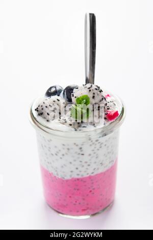 Un puding au chia superposé avec garniture rose sur fond blanc. Concept de petit déjeuner sain. Banque D'Images