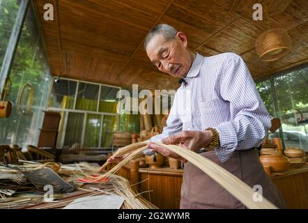 (210613) -- CHENGDU, 13 juin 2021 (Xinhua) -- Zhao Sijin choisit des bandes de bambou dans le village de Zhuyi du canton de Daoming à Chongqing, dans la province du Sichuan, dans le sud-ouest de la Chine, 1er juin 2021. Zhao Sijin a travaillé avec la préoccupation, ses doigts se déplaçant sans arrêt avec deft, jusqu'à ce que les bandes de bambou à la main soient tissées dans une belle pièce d'art. comme si par la magie, le bambou weaver, maintenant 86, n'avait jamais échoué à captiver chaque témoin de son savoir-faire superbe. Zhao est originaire de Daoming, un canton du sud-ouest de la Chine, mieux connu pour ses bandes de bambou. Avec une histoire qui remonte à environ 2,000 ans, Banque D'Images