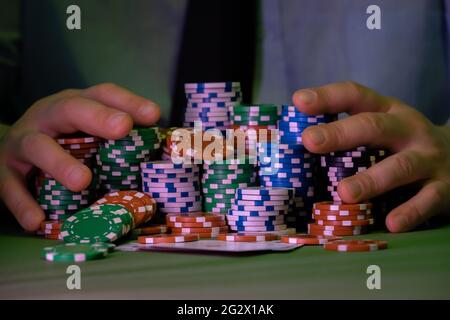 L'homme joue dans le casino. Seuls les jetons et les mains sont visibles au-dessus de la table. L'arrière-plan est très flou. Banque D'Images