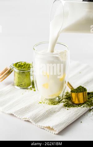 Verser le lait dans le verre pour préparer le thé au matcha Latte Banque D'Images