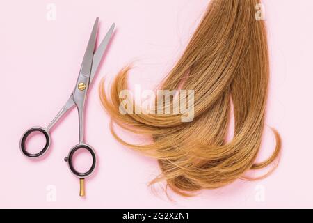 Fil de cheveux et de ciseaux pour enfants sur fond rose, vue du dessus. Banque D'Images