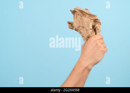 Concept de recyclage et écologie. La main tient les déchets de papier sur fond bleu. Banque D'Images