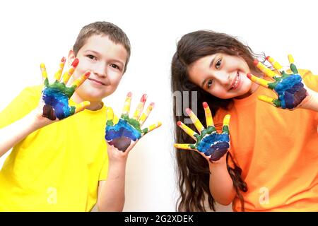 un garçon et une fille de 10 ans regardent la caméra et montrent leurs palmiers dans des peintures. Rainbow sur les mains. Le concept d'une enfance et d'un childre heureux Banque D'Images