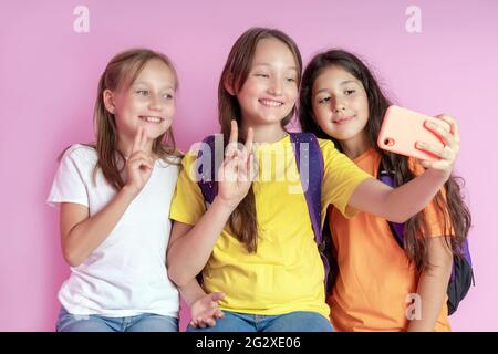 Trois adolescentes souriant et filme une vidéo sur fond rose. Selfies Banque D'Images