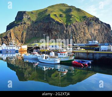 Bateaux de pêche de différentes tailles à leurs morrings dans le port de Heimaey à Vestmannaeyar, le groupe insulaire au large de la côte sud de l'Islande Banque D'Images