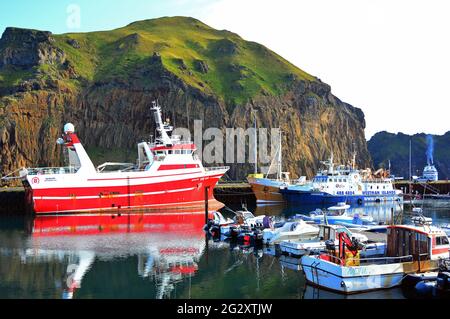 Bateaux de pêche de différentes tailles à leurs morrings dans le port de Heimaey à Vestmannaeyar, le groupe insulaire au large de la côte sud de l'Islande Banque D'Images