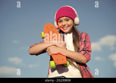 Juste un peu plus de plastique sous le pied. Bonne patineuse sur ciel bleu. Un petit enfant tient une planche de sou. Planche à roulettes Penny. Vitesse et équilibre. Été Banque D'Images