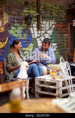 jeune couple ayant un bon moment assis dans un café en plein air avec leur chien. espace de copie, image de foyer sélectif. Banque D'Images