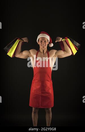 Achats de puissance. Sac à papier de bonne tenue de père noël fléchissant les bras musclés. Achats de vacances. Lendemain de Noël. Boutique de fitness. Noël et nouvel an. Vente et Banque D'Images