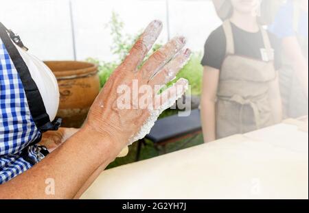 Le cuisinier enseigne aux enfants à faire des beignets sucrés. La main femelle au premier plan attire l'attention. Cuisiner à la maison. Classe de maître dans la cuisson. Banque D'Images