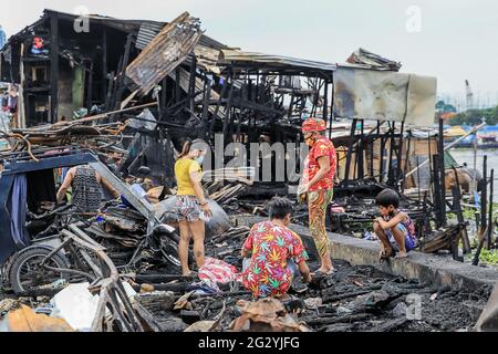 Manille, Philippines. 13 juin 2021. Les résidents recherchent des biens dans une maison charrée après qu'un bidonville le long de la rivière Pasig a pris feu à partir d'un navire de cargaison en feu à Manille, aux Philippines, le 13 juin 2021. Dans un rapport, la Garde côtière des Philippines (PCG) a déclaré que l'incendie a éclaté vers 9 heures, heure locale, samedi, lorsqu'un petit cargo ravitaillait près d'un pont dans la ville de Manille. Crédit: Rouelle Umali/Xinhua/Alamy Live News Banque D'Images