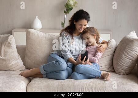 Bonne maman latine et fille biraciale parlent sur smartphone Banque D'Images