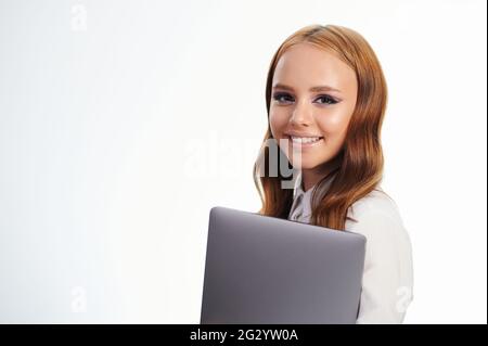 Portrait d'une jeune fille cloueuse heureuse avec ordinateur portable isolé sur fond blanc de studio Banque D'Images