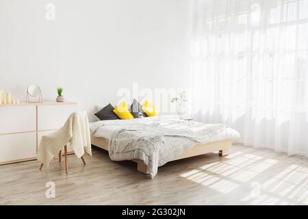 Chambre confortable et féminine avec oreillers et plantes au mur blanc Banque D'Images