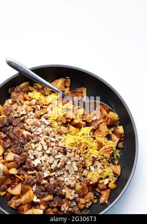 Garniture de pomme dans une casserole avec des noix, de la cannelle, des raisins secs et du zeste de citron pour strudel isolé sur fond blanc.directement au-dessus.Ingrédients pour le gâteau. Banque D'Images