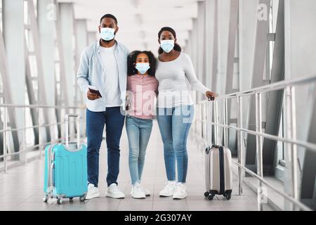 Famille noire dans les masques de voyage, tenant des documents posant à l'aéroport Banque D'Images