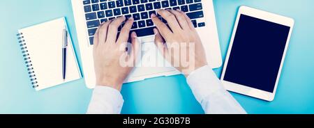 Main d'homme d'affaires travaillant sur un ordinateur portable avec une tablette et un ordinateur portable sur le bureau, clavier de saisie manuelle avec livre et stylo, espace de travail avec copie Banque D'Images