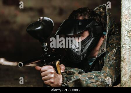 Jeune homme en action paintball avec équipement professionnel, masque, pistolet et casque de protection, simuler le combat militaire à l'aide de pistolets pneumatiques pour tirer Banque D'Images