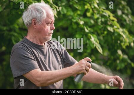 Homme âgé pulvérisant ou utilisant un répulsif contre les insectes, les moustiques et les tiques dans la forêt, spray protecteur, concept de soins de santé Banque D'Images