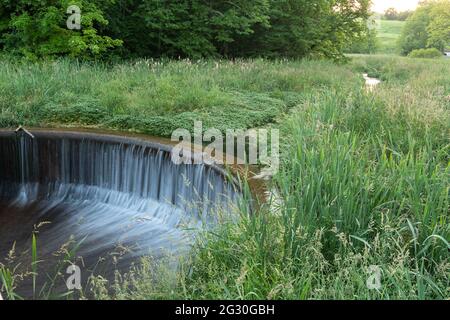 Longue exposition d'eau en cascade sur un déversoir le long d'un ruisseau Banque D'Images