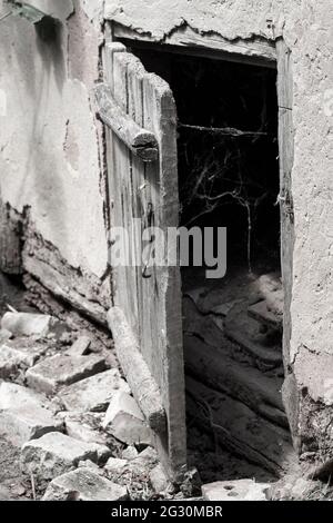 Porte en bois légèrement ouverte et toile d'araignée à l'ancienne sur un fond sombre. Marquage du fond Banque D'Images