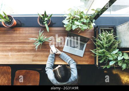 Vue de dessus. Une fille adulte utilise un ordinateur portable et un téléphone avec un écran blanc pour une maquette Banque D'Images
