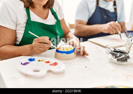 Peintre hispanique d'âge moyen peint en couple dans un studio d'art. Banque D'Images