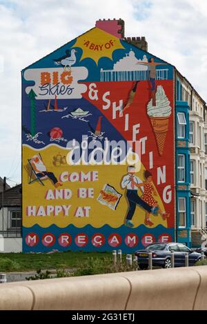 Sandylands Promenade, Heysham, Morecambe, Lancashire, Royaume-Uni. 9 juin 2021. Toujours caché derrière la peinture murale commandée par la publicité deco de Morecambe et peinte par Cobalt collective avec les artistes Erin Bradley-Scott et Kat Lowdon de la Cobalt collective mettant la touche finale à la peinture murale Shiftings Sands qui a été peinte sur le pignon d'une maison sur Sandylands Promenade la murale, qui est l'œuvre de l'artis et Morecambes Deco publique de Glasgow, rappelle les jours de gloire de Morecambes en tant que station balnéaire prospère crédit: PN News/Alamy Live News Banque D'Images