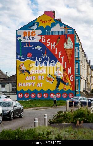 Sandylands Promenade, Heysham, Morecambe, Lancashire, Royaume-Uni. 9 juin 2021. Toujours caché derrière la peinture murale commandée par la publicité deco de Morecambe et peinte par Cobalt collective avec les artistes Erin Bradley-Scott et Kat Lowdon de la Cobalt collective mettant la touche finale à la peinture murale Shiftings Sands qui a été peinte sur le pignon d'une maison sur Sandylands Promenade la murale, qui est l'œuvre de l'artis et Morecambes Deco publique de Glasgow, rappelle les jours de gloire de Morecambes en tant que station balnéaire prospère crédit: PN News/Alamy Live News Banque D'Images