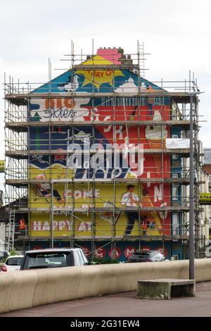 Sandylands Promenade, Heysham, Morecambe, Lancashire , Royaume-Uni, Image de fichier : 9 juin 2021 encore caché derrière la peinture murale commandée par Morecambe Deco publique et peinte par Cobalt collective avec les artistes Erin Bradley-Scott et Kat Lowdon de la Cobalt collective mettant la touche finale à la peinture murale Sables qui a été peinte sur le pignon d'a House on Sandylands Promenade la murale qui est l'œuvre de l'artis et Morecambes canbe Deco publique de Glasgow est un rappel aux jours de gloire de Morecambes comme station balnéaire prospère Banque D'Images