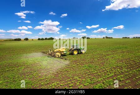 Vetrino, Bulgarie - 6 juin 2021 image aérienne d'un tracteur pulvérisant des jeunes cultures au printemps sur le terrain avec un tracteur John Deere 6930. Banque D'Images